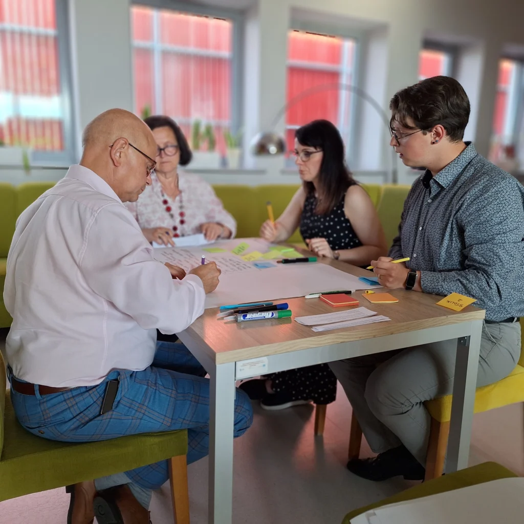 grupa osób przy stole pracujących nad dużą kartką